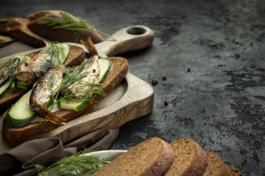 Ahşap sunucuda tütsülenmiş lahanalı sandviçler ve siyah arka plan. Kopyalama alanı olan bir sandviç .