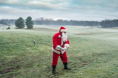 Geleneksel kırmızı kostümlü Noel Baba sabahın erken saatlerinde golf sahasında oynar..