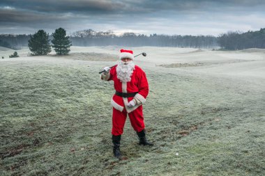 Geleneksel kırmızı kostümlü Noel Baba sabahın erken saatlerinde golf sahasında oynar..