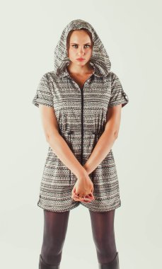 Siyah beyaz tulumlu genç bir kadının portresi düz ve sert görünüyor, beyaz arka planda duruyor, stüdyo çekimi..