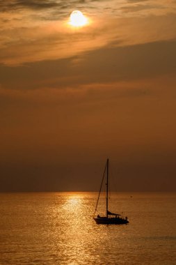 Kanarya Adası Fuerteventura 'daki Morro Jable plajına yakın altın ışıkta, gün batımında okyanusta yelkenliye bakın..