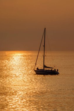 Kanarya Adası Fuerteventura 'daki Morro Jable plajına yakın altın ışıkta, gün batımında okyanusta yelkenliye bakın..