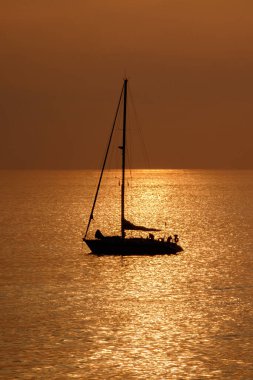 Kanarya Adası Fuerteventura 'daki Morro Jable plajına yakın altın ışıkta, gün batımında okyanusta yelkenliye bakın..