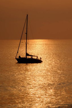 Kanarya Adası Fuerteventura 'daki Morro Jable plajına yakın altın ışıkta, gün batımında okyanusta yelkenliye bakın..