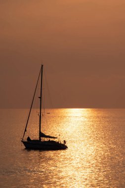 Kanarya Adası Fuerteventura 'daki Morro Jable plajına yakın altın ışıkta, gün batımında okyanusta yelkenliye bakın..
