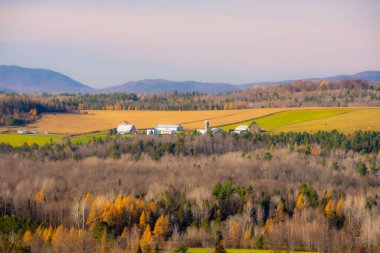 Dağları, tarlaları ve çiftliği olan güzel bir manzara.