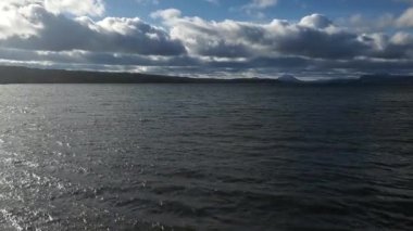 Dalgalı su, uzak dağlar ve bulutlu gökyüzü ile Memphremagog gölünün görüntüleri