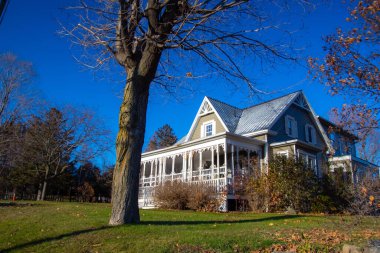 Çıplak ağaçlar ve mavi gökyüzü olan eski evin güzel manzarası.