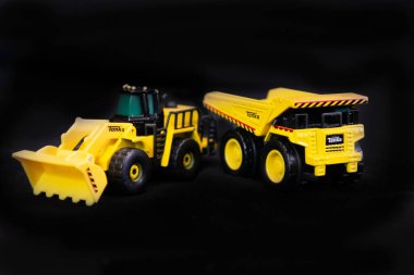 Siyah arka planda sarı oyuncak kamyonlar