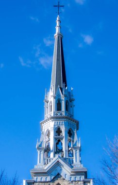 Mavi gökyüzü arka planında parlak güneş ışığı altında Katolik kilise kulesi.