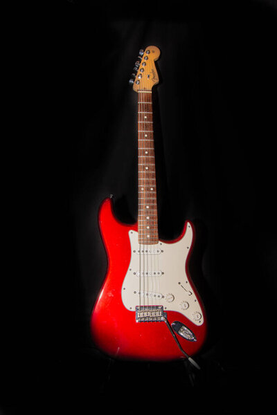 Red electric guitar on black background