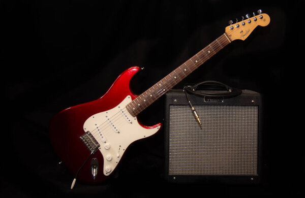 Electric guitar with combo amp on black background