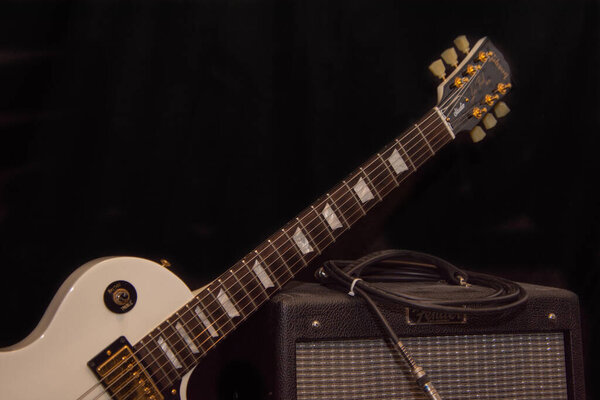 Electric guitar with combo amp on black background