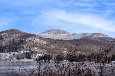 Güzel kış manzarası gölü, çıplak ağaçlar ve karlı tepeler.