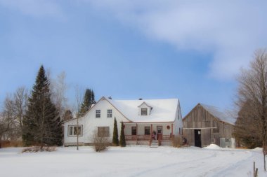 Mavi bulutlu gökyüzü altında çiftlik binaları olan kış manzarası