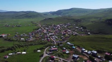 Köyün tepeden, arkadan ve geniş açılı insansız hava aracı görüntüsü kırsal bölgedeki nehir tarafından çekildi.