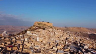 Eski binalarla dolu bir şehir, şehrin tepesindeki dağın yakınındaki kalenin insansız hava aracı görüntüsü.