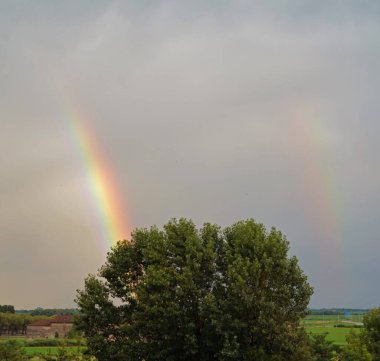 Vercelli, İtalya - 06022020: Şiddetli bir fırtınadan sonra çift gökkuşağı gökyüzüne doğru yükselir