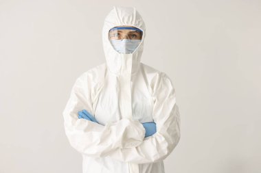 Kadın doktor ya da bilim adamı koruyucu elbise, maske ve beyaz arka planda katlanmış kolları olan gözlük takıyor.