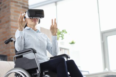 Kadın, sanal gerçeklik gözlükleriyle tekerlekli sandalyede oturuyor.