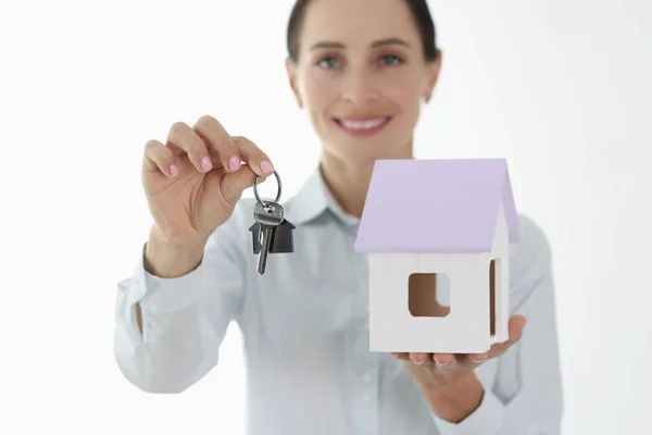Sorrindo agente feminina segurando pequena casa e chaves — Fotografia de Stock