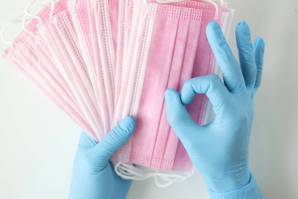 Doctor en guantes azules desechables tiene muchas máscaras médicas y el gesto es excelente —  Fotos de Stock