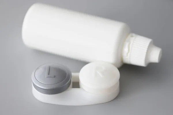 Recipiente de armazenamento para lentes de contato macias e garrafa de solução na mesa — Fotografia de Stock