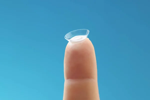 Soft contact lens on female finger on blue background — Stock Photo, Image