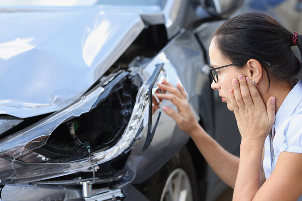 Женщина-водитель смотрит на разбившуюся машину. Последствия концепции ДТП