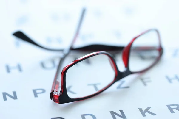 Stylish glasses in black and red frames lie on ophthalmic table closeup — Stock Photo, Image