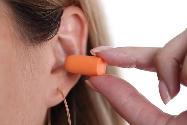 Mujer inserta tapones naranjas en los oídos de cerca — Foto de Stock