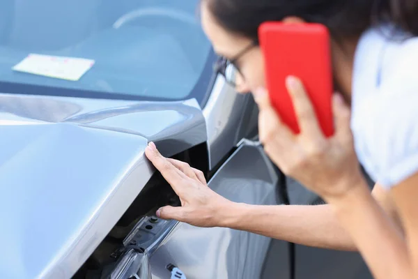 Autofahrerin telefoniert mit Smartphone und begutachtet Schaden am Auto nach Unfall — Stockfoto