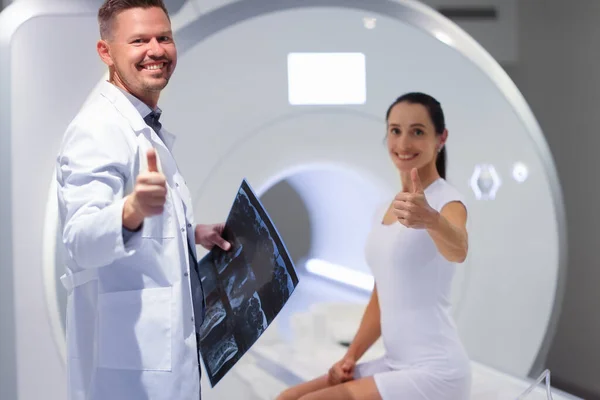 Молодой врач и пациентка держат большие пальцы в комнате МРТ — стоковое фото