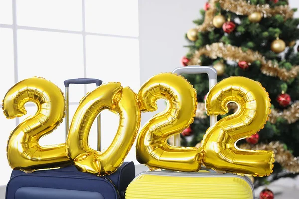 Золотые гелиевые шарики с номерами 2022 стоят на чемоданах Рождественская елка крупным планом — стоковое фото