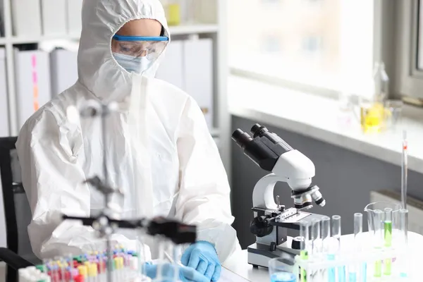 Scientifique en combinaison de protection, masque et gants effectue des recherches en laboratoire — Photo