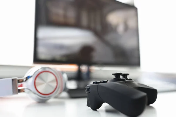 Hra joystick se sluchátky ležet na stole s počítačem monitor detailní — Stock fotografie
