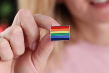 Elinde lgbt bayrağı olan bir kadın var.