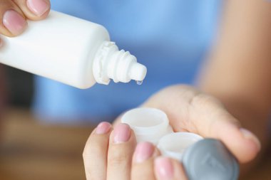 Kadın, plastik kaplara mercek sıvısı döküyor.