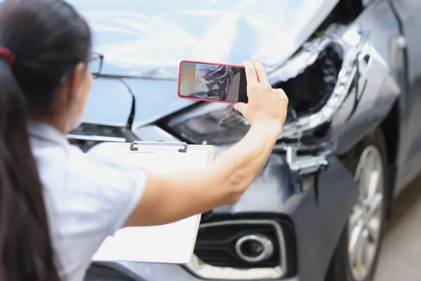 Versicherungsvertreterin fotografiert kaputtes Auto auf Handy-Nahaufnahme — Stockfoto