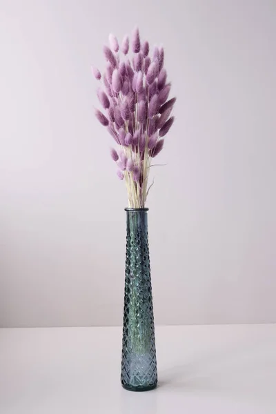 Glasvase mit lila getrockneten Blumen auf Tischhintergrund — Stockfoto