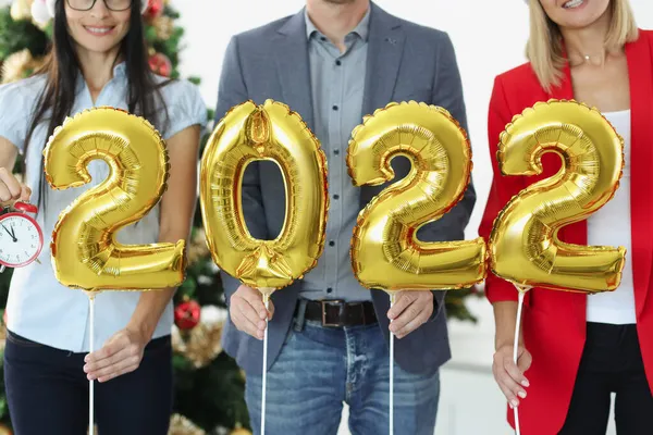 İş adamlarının elinde 2022 yılbaşı ağacının arkaplanındaki çalar saat numaraları var.