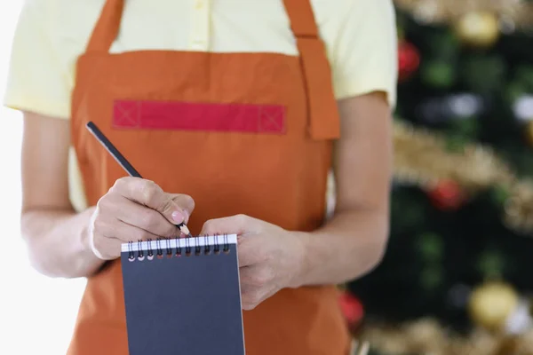 Donna cameriera in uniforme prende ordine sullo sfondo dell'albero di Capodanno — Foto Stock