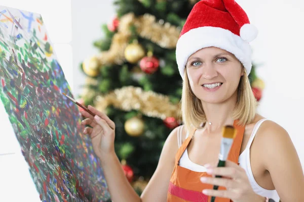 Ritratto di giovane donna artista sorridente dipinto quadro sullo sfondo dell'albero di Capodanno — Foto Stock