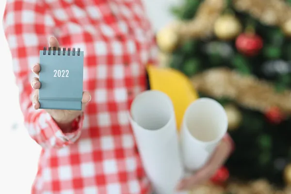 La mano de la mujer sostiene el calendario para 2022 y el sombrero duro con rollo de papel — Foto de Stock