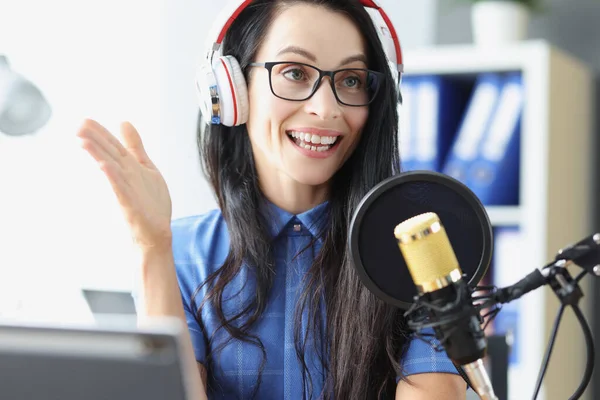 Woman presenter of radio with headphones speaking into microphone in studio — Stock Photo, Image