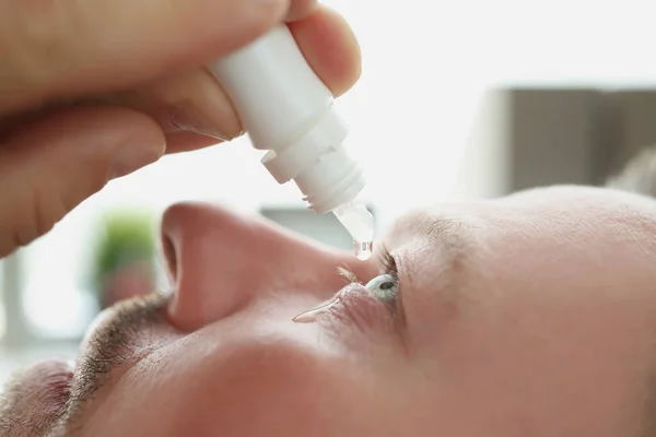 Man druipt antibacteriële druppels in zijn oog close-up — Stockfoto