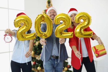 İş adamlarından oluşan bir grup altın helyum balonu tutuyor ve arka planda 2022 numara var.