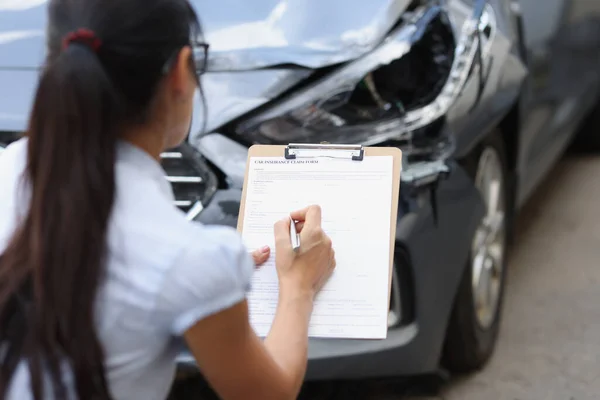 Versicherungsvertreterin füllt Antragsformular in der Nähe von Autowracks aus — Stockfoto