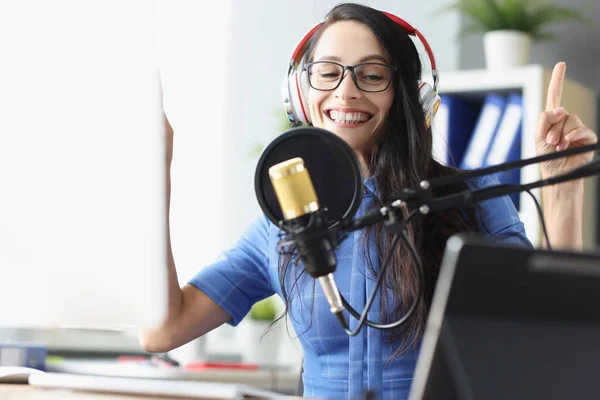 Smiling presenter woman in headphones speaking into microphone in studio — Stock Photo, Image