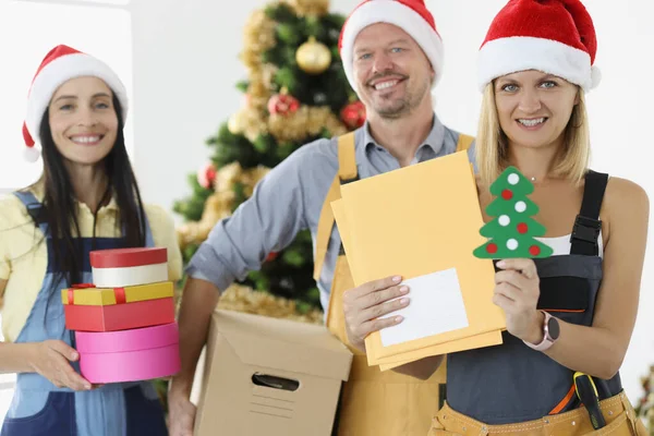 Grupo de carteiros em chapéus de Papai Noel vermelho segurando letras e caixas com presentes — Fotografia de Stock